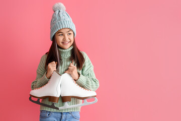 Little Asian girl in warm clothes with ice skates on pink background
