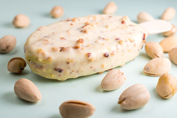 Some pistachios and pistachio ice cream with pistachio bits on blue background 