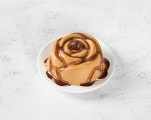 Coffee Panna Cotta in the shape of a rose with chocolate sauce, on a plate. Light gray background
