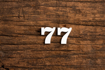 Number 77 in wood, isolated on rustic background