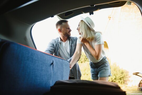 Couple putting suitcases in car trunk for a journey