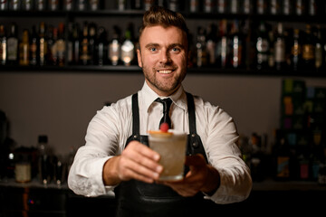 bartender serving a glass with fresh foamy and decorated cocktail to you