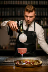 Handsome bartender is concentrated on making smoke air bubble