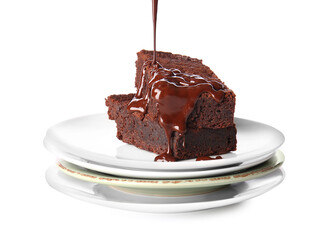 Pouring of chocolate topping onto plates with tasty brownies on white background