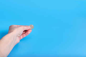 Russian ruble money, coins in a female hand on a blue background. Copy space