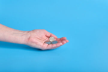 Russian ruble money, coins in a female hand on a blue background. Copy space