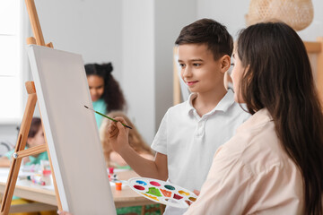 Cute boy and teacher during master-class in art