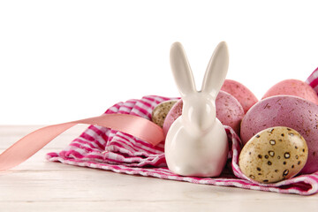 Painted Easter eggs and figurine of bunny on table against white background