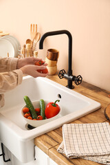Woman washing cherry tomatoes over sink in kitchen