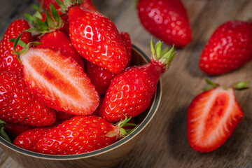 Fresh strawberries in a bowl on wooden table with low key scene