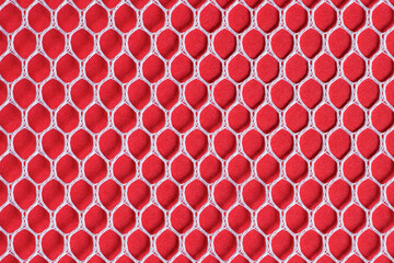 White laundry and sport mesh on red background. The fabric texture with hexagon shape stitching....