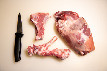 Boning a shoulder of lamb leg meat on a wooden tray, white background, Top view