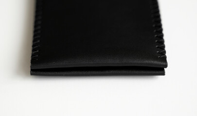 Empty black men's money clip handmade leather wallet with a two pockets for cards lies on a white table. Selective focus, copy space, close up.