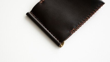 Empty brown men's money clip handmade leather wallet with a two pockets for cards lies on a white table. Selective focus, copy space, close up.