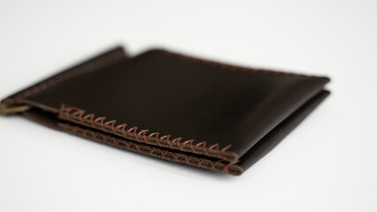 Brown men's money clip handmade leather wallet. Empty money clip wallet with a two pockets for cards lies on a white table. Selective focus, copy space.