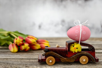 Toy car with an Easter egg and tulips