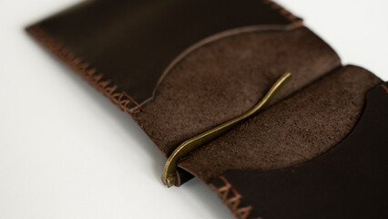 Open brown men's money clip handmade leather wallet. Close up. Empty money clip wallet with a two pockets for cards lies on a white table. Selective focus, copy space.