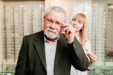 an elderly man with an ophthalmologist chooses glasses in the optics salon.