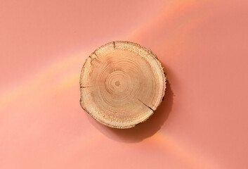 Woodcut lying on a trendy pink background. A wooden platform for luxury and natural cosmetics or...