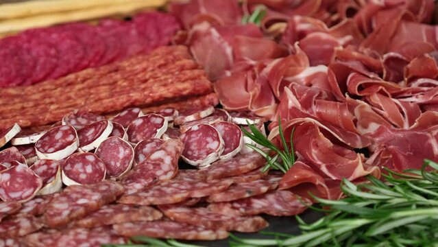 Meat plate with assortment of various tasty Spanish, french or Italian appetizers - sliced prosciutto, sausage, ham, boiled pork, balyk, jamon, sandwich, cheese, salami. Meat platter rotating