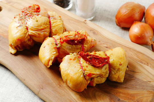 Rolled corn fed chicken thigs with herbs on a wooden board. Poultry product.