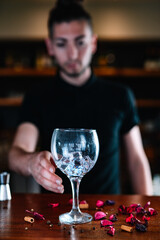 Detail of the hands of a waiter leaving a crystal glass on the bar, to prepare a mixed drink.