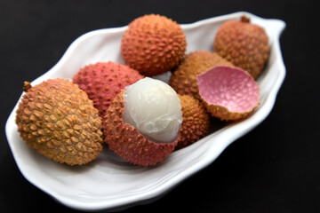 A plate with lychees on a black surface