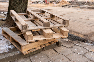 Old worn-out wooden pallets at a construction site in the city. Repair of the city street and sidewalk.