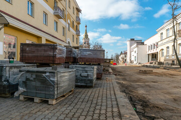 New paving slabs neatly stacked on pallets. Repair of sidewalks and replacement of paving slabs. Reconstruction of urban infrastructure.