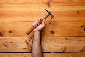hand grabbing tinsmith hammer on light wooden background - Labor Day