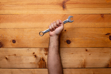 hand grabbing wrench on light wooden background - Labor Day