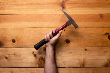 Arm holding geological hammer on light wooden background - Labor Day