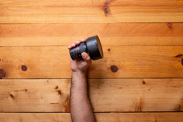 hand grabbing camera lens on light wood background - Labor Day - Powered by Adobe