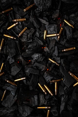 Empty shells from weapons on black smoldering coals. Consequences of the war. Dark back. - obrazy, fototapety, plakaty
