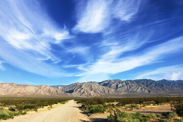 dramatic sky desert mountains blue clouds mountain range hiking trail summer season dirt road landscape