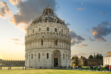 Fototapeta na wymiar Sunset on the Piazza dei Miracoli or Field of Miracles as tourists sightsee near the Baptistery of St. John in Pisa Italy