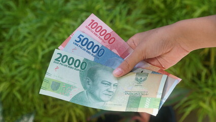 The Indonesian currency, the 20,000, 50,000 and 100,000 rupiah notes, are held in the hands of a...