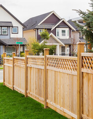 Nice wooden fence around house. Wooden fence with green lawn and trees.