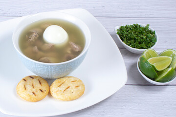 Chicken consomme, traditional Colombian food, accompanied by hard-boiled egg, corn arepas, cilantro and lemon