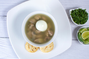 Chicken consomme, traditional Colombian food, accompanied by hard-boiled egg, corn arepas, cilantro and lemon