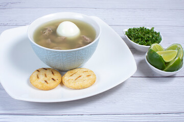 Chicken consomme, traditional Colombian food, accompanied by hard-boiled egg, corn arepas, cilantro and lemon
