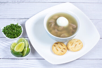 Chicken consomme, traditional Colombian food, accompanied by hard-boiled egg, corn arepas, cilantro and lemon