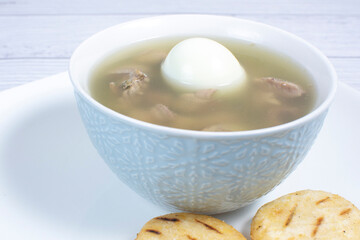 Chicken consomme, traditional Colombian food, accompanied by hard-boiled egg, corn arepas, cilantro and lemon