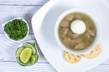 Chicken consomme, traditional Colombian food, accompanied by hard-boiled egg, corn arepas, cilantro and lemon