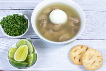 Chicken consomme, traditional Colombian food, accompanied by hard-boiled egg, corn arepas, cilantro...