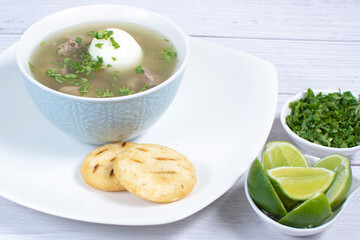 Chicken consomme, traditional Colombian food, accompanied by hard-boiled egg, corn arepas, cilantro and lemon
