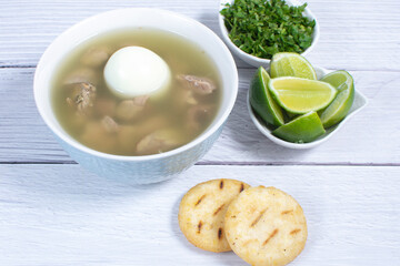 Chicken consomme, traditional Colombian food, accompanied by hard-boiled egg, corn arepas, cilantro and lemon