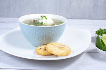 Chicken consomme, traditional Colombian food, accompanied by hard-boiled egg, corn arepas, cilantro and lemon