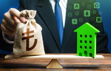 Businessman puts turkish lira money bag on scales and green house. Investment in renovation....