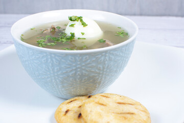 Chicken consomme, traditional Colombian food, accompanied by hard-boiled egg, corn arepas, cilantro and lemon
